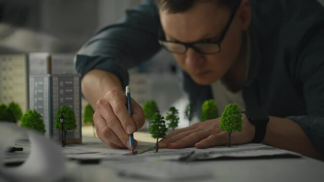 The design specialist in the design center actively operates a compass for precise measurements. He develops innovative projects for residential complexes and architectural structures