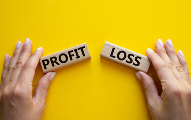 Profit or Loss symbol. Concept word Profit or Loss on wooden blocks. Businessman hand. Beautiful...