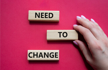 Need to change symbol. Concept words 'Need to change' on wooden blocks. Beautiful red background. Businessman hand. Business and Need to change concept. Copy space.
