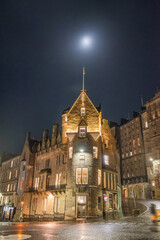 Fototapeta na wymiar A night scene of old buildings on the corner of Market Street and Cockburn Street, under the moon. Edinburgh, Scotland