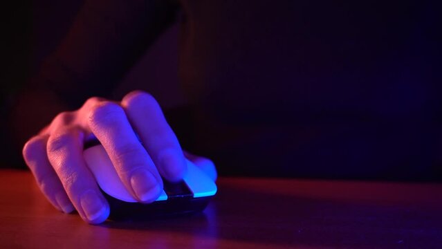 female hand controls a computer mouse on a dark background with red and blue backlighting 