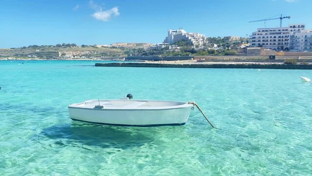 Small boat floating on the crystal clear emerald water mediterranean sea. Qawra Malta. High quality 4k footage