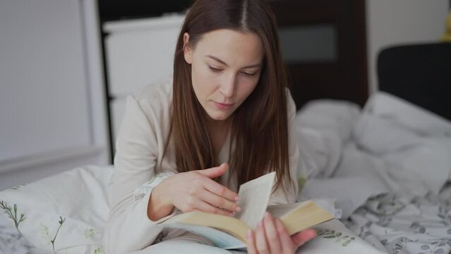 Young Woman Enjoying a Good Book in Bed