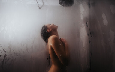 A peaceful scene capturing a young woman embracing the warmth and comfort of a steaming shower, as water cascades over her.
