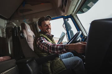 Happy confident male driver sitting in  his truck, using his tablet