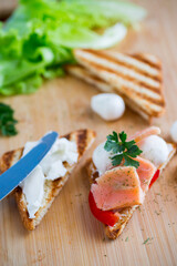 fried toast with salmon, cream cheese, salad, on a wooden table