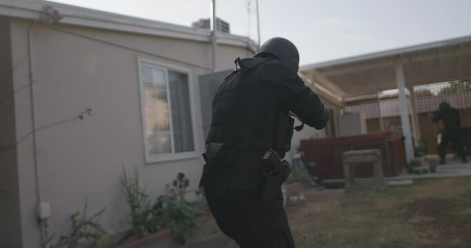 Swat team breaches fence at urban house, looking around corner, readying a home breach, Moving fast, Action