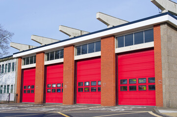 Fire brigade station building with red roller shutter doors - obrazy, fototapety, plakaty