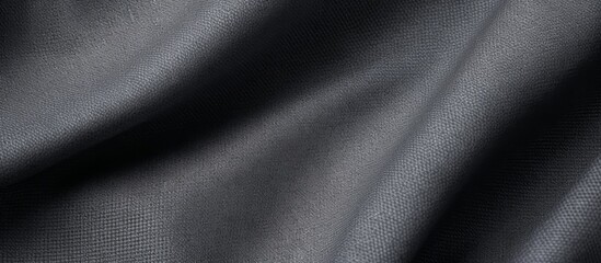 A macro photograph of a black cloth with subtle waves in shades of grey, creating a mesmerizing pattern. The metallic rim adds a touch of darkness, contrasting beautifully with the electric blue tint