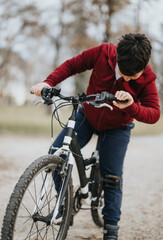 A cheerful young boy rides his bicycle in a city park, immersed in greenery and the freedom of nature.