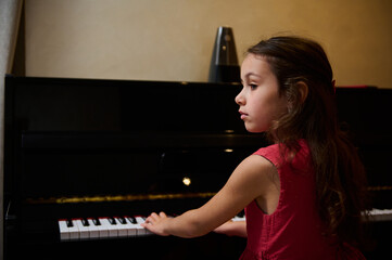 Little pianist musician girl playing piano and singing song, creating music, performing and...