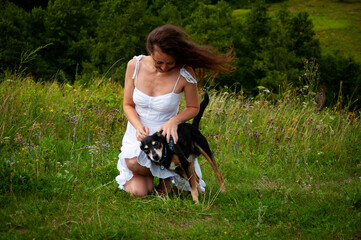 Woman and dog in mountain valley. Landscape of summer nature. Happy girl play with dog in valley outdoor. Carpathians woman with dog. Woman and dog on green grass. Nice walk