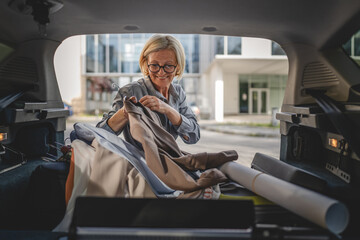 mature blonde woman travel take stuff belongings from the back of car