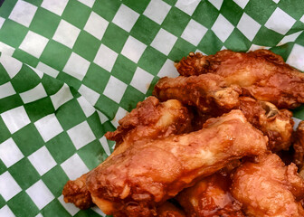Naked buffalo wings in a basket with green and white checkered wax paper