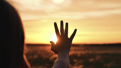 Woman stretched out hand sunset silhouette. Palm arm towards sun catching rays of evening morning...