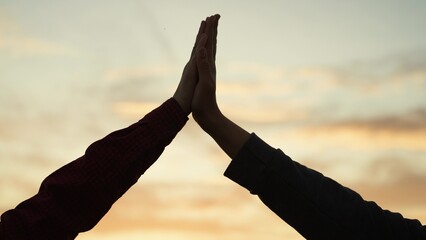 High five hands at sunset silhouette. Best friends buddies clapping each other palms in field park...