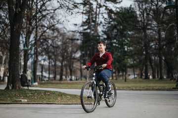 Fototapeta na wymiar A happy boy rides his bicycle through a leafy urban park, enjoying the freedom and joy of a relaxing weekend outdoors.