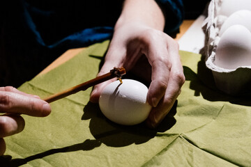 hand holding a egg and making traditional beeswax eggs painting