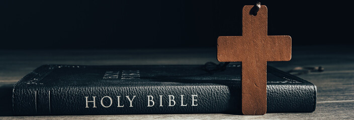 Holy Bible and wooden cross on table