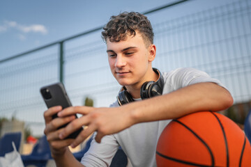 caucasian teen using mobile phone smartphone at a basketball court
