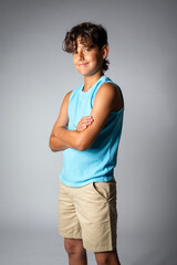 Portrait of a smiling boy with arms crossed, wearing khaki shorts and a blue tank top