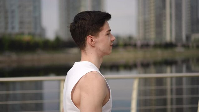 A young guy is jogging in the city park along the river in the morning