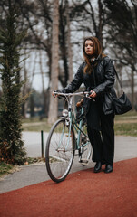 Confident and attractive young woman in elegant business attire standing with a classic bicycle outdoors.