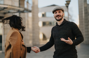 A cheerful man in a sweater and cap is holding hands with a woman in a coat, walking and chatting...