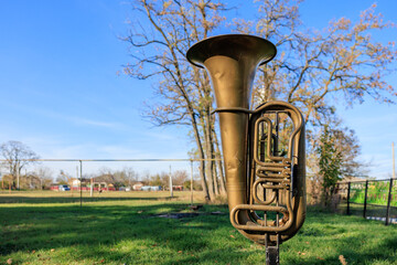 A large brass instrument is sitting in a grassy field