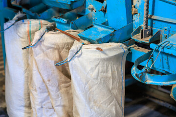 Three bags of white material are hanging from blue machine