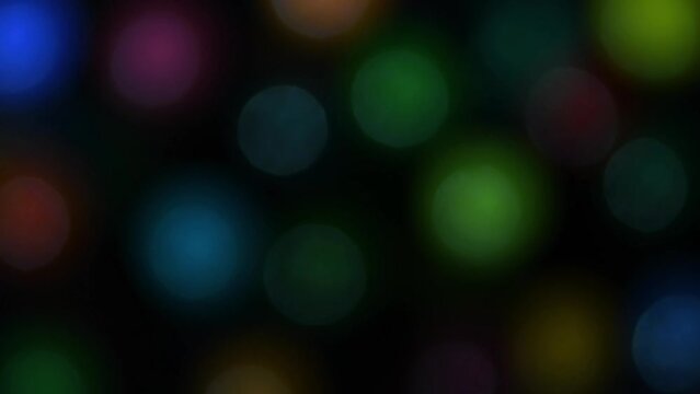 Fast moving repetitious multicoloured out of focus round bokeh constantly pulsating on black background