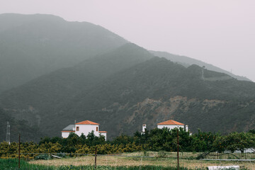  Rustic homes nestled in the lush greenery of the Spanish countryside, beneath a mountainous...