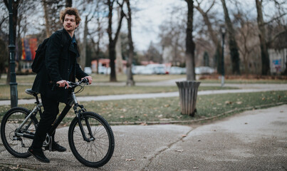 A modern businessman in smart attire parks his bicycle and prepares to walk in an urban park environment.