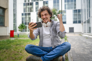 man use mobile smart phone play video games sit outdoor