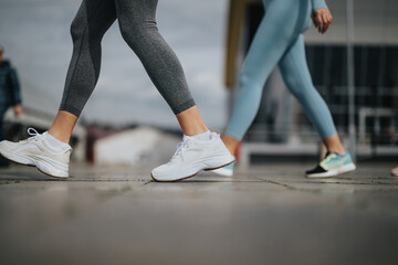 Close-up of female legs in motion, wearing sports shoes on a city street, embodying an active lifestyle.