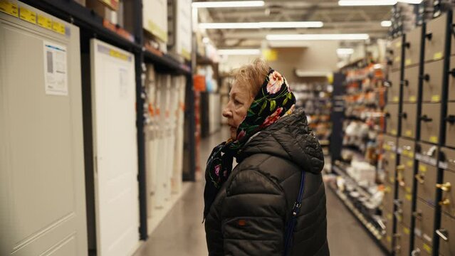 Elderly lady pushing cart in retail store for doors and repair works