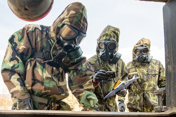 Three men in hazmat suits are surveying possible chemical agents.
