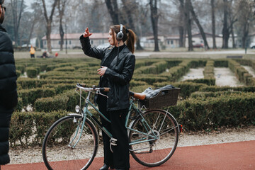 Confident and stylish young woman enjoying music with headphones while standing with her bicycle in an urban park setting.