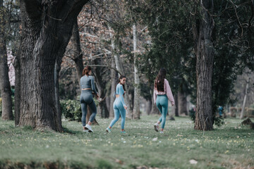 Fototapeta premium Three female athletes in sportswear exercising by jogging in a serene park setting, showcasing teamwork and dedication to fitness.