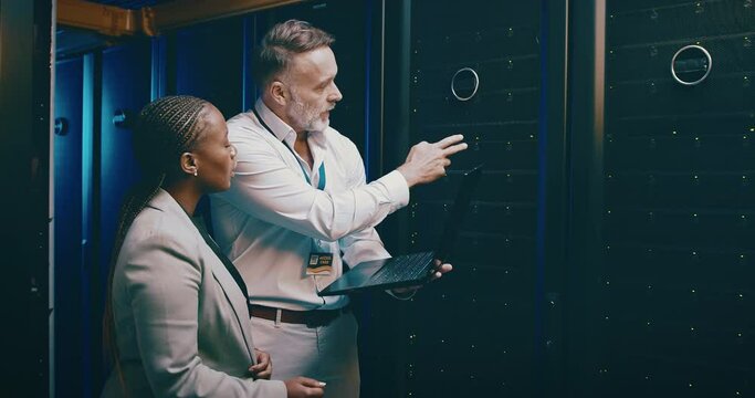 Technician, teamwork and laptop in server room for cloud computing, system engineering and hardware solution. Senior man, woman or people in data center, information technology coding or programming
