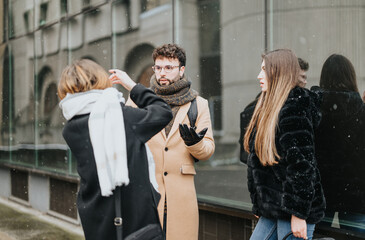 A group of young business colleagues engage in a conversation outside on a snowy day, showcasing teamwork and winter corporate lifestyle.