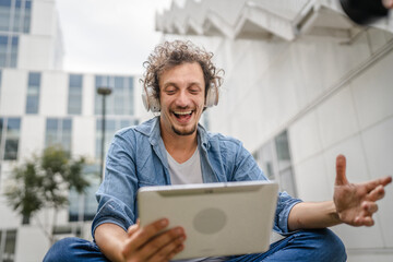 man sit in front of modern building use digital tablet watch movie