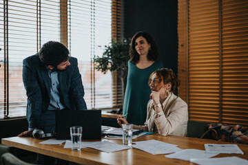 Three colleagues engage in a collaborative discussion over company paperwork and reports, conveying teamwork and strategy in a professional office environment.