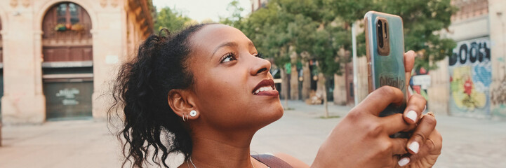 Young mixed race woman uses cell phone, takes photo of the old city, Panorama - obrazy, fototapety, plakaty