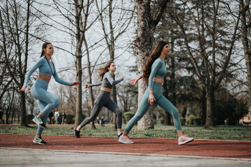 Active women running outdoors on a track surrounded by trees, displaying energy and teamwork.