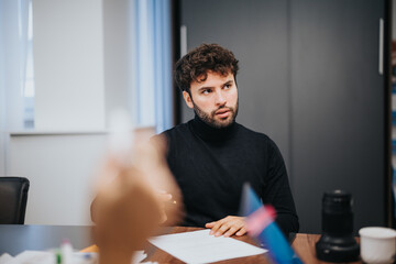 A young male person attentively listens during a business meeting, illustrating teamwork and communication in a corporate setting.