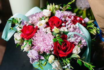 Elegant Bouquet with Red Roses and Pink Blooms. A vibrant bouquet featuring red roses, pink chrysanthemums, and delicate white flowers, tied with a soft blue ribbon.