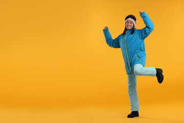 Winter sports. Happy woman with snowboard goggles on orange background, space for text - Powered by Adobe