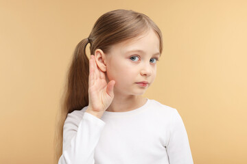 Little girl with hearing problem on pale brown background
