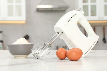 Modern mixer, eggs and bowl with flour on white marble table in kitchen